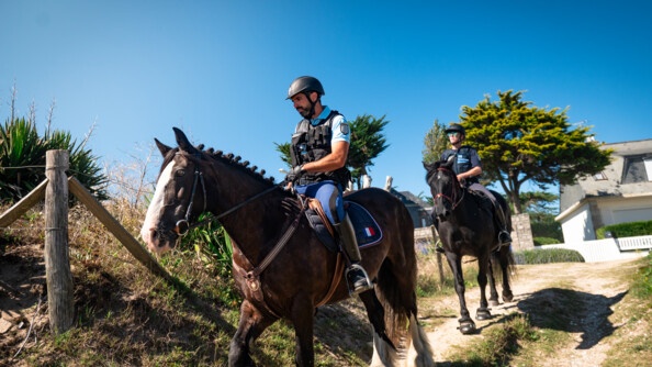 Un gendarme et une policière municipale surveillent une plage à cheval.