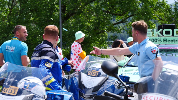 Vue sur les motos et trois gendarmes échangeant avec le sourire, dont un motard et un garde républicain