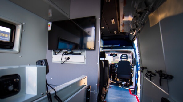 L'intérieur du nouveau véhicule de commandement et de transmission de la gendarmerie nationale, vu de l'arrière, avec à gauche l'écran de télévision.