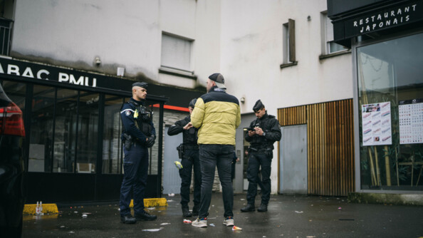 Trois gendarmes procèdent au contrôle d'un piéton au pied de bâtiments