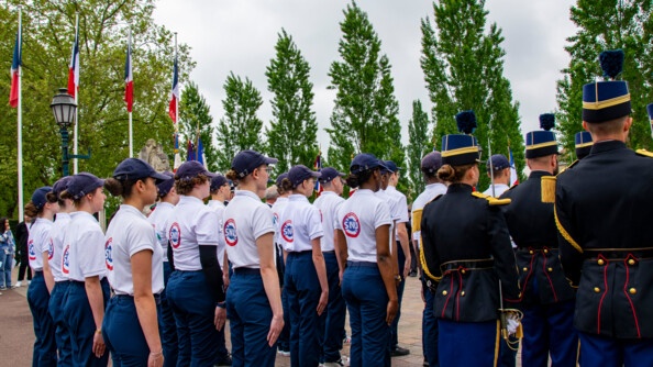 Des jeunes du service national universel alignés de dos aux côtés des élèves officiers de la gendarmerie en tenue de tradition.