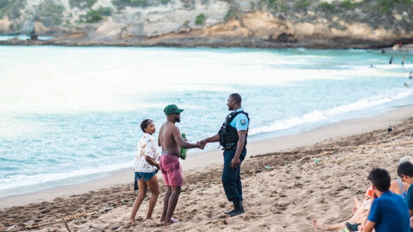 Un réserviste sert la main d'un homme qui marche aux côtés d'une femme sur la plage.
