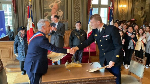 Poignée de main entre le maire de Courbevois, à gauche, et le chef d’escadron, commandant l’EGM 16/1, à droite, de part et d'autre d'une table ancienne.