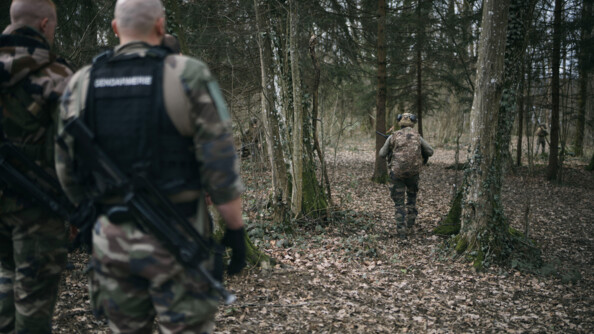 Quatre gendarmes et militaires en treillis marchent dans la forêt