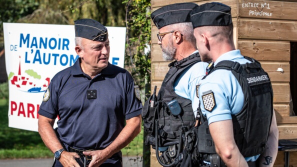 A gauche, un général de gendarmerie en tenue bleu marine, échange avec deux gendarmes en tenue d'intervention et gilet pare-balle, qui le regardent