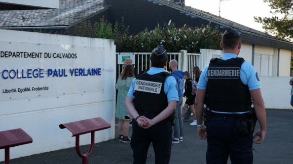 Deux gendarmes devant l'entrée d'un collège.