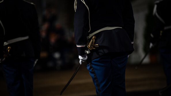 Zoom sur une main de gendarme en tenue de cérémonie tenant un sabre