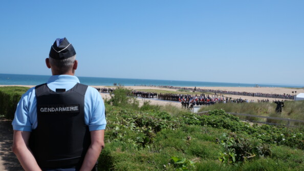 Un gendarme en surveillance de la cérémonie depuis les dunes de la plage.