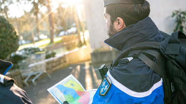 Un gendarme tient une carte du territoire divisée en zones de couleur