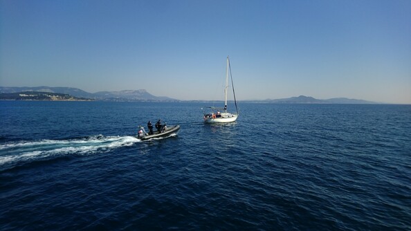 Contrôle d'un voilier en Méditerranée par deux gendarmes maritimes à bord d'un semi-rigide.