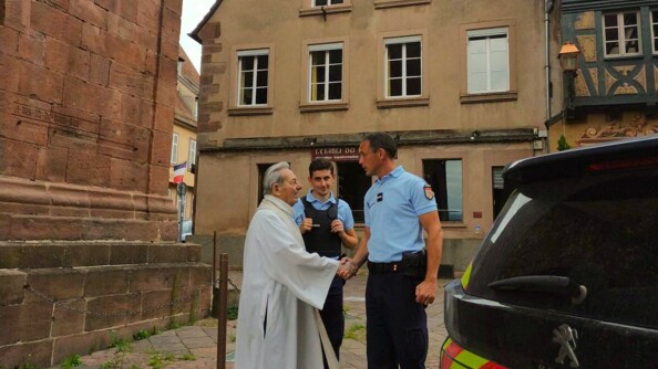 Deux gendarmes échangent avec un prêtre devant l'église de Saverne.