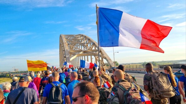 Les gendarmes traversent le pont en arborant fièrement des drapeaux français.