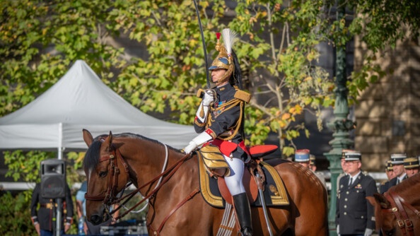 Une colonel de gendarmerie à cheval, vue de trois-quart gauche, en train de saluer au sabre