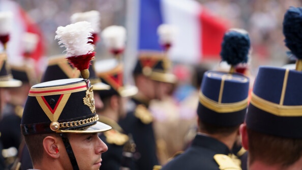 En uniforme de cérémonie, à gauche un garde républicain et à droite un élève de l'EOGN. En fond, un magnifique drapeau français qui flotte au vent.