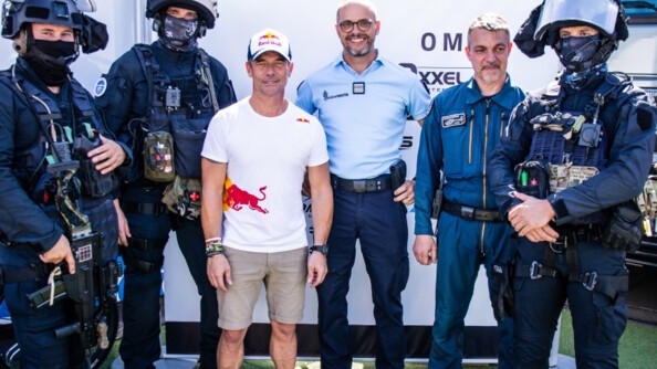 Au centre de l'image, en t-shirt blanc et bermuda beige, Sébastien Loeb. A gauche, deux militaires du GIGN en tenue d'intervention. A droite, un colonel de gendarmerie, un pilote de gendarmerie et un troisième homme du GIGN