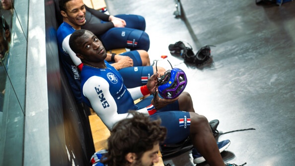 Timmy Gillion assis sur un banc entre deux autres membres de l'équipe de France de cyclisme sur piste.