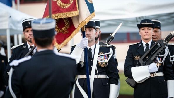 Des gendarmes de l'armement en tenue de cérémonie avec en premier plan un militaire de dos puis un autre, porte-drapeau