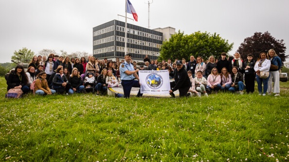 1 - Sur l'herbe, devant le drapeau français, une centaine de familles et d'enfants posent autour du fanion des Képis Pescalunes, tenu par un gendarme et un homme vêtu de noir