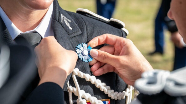 Mise en place d'un bleuet de France sur une vareuse gendarmerie par deux élèves