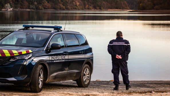 Un gendarme de la COB de Guerlédan, dans les Côtes d'Armor, avec son véhicule de service, au bord du lac de Guerlédan.