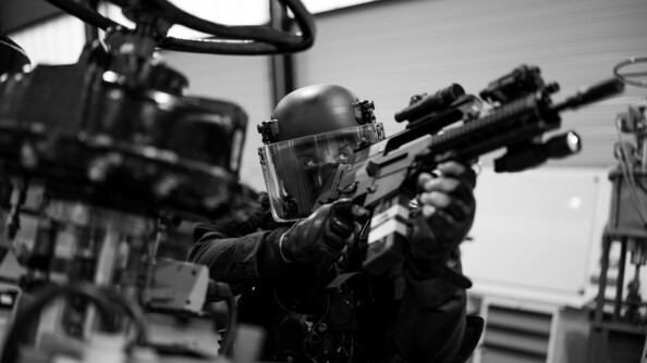 Photo en noir et blanc d'un militaire du PSPG armé.