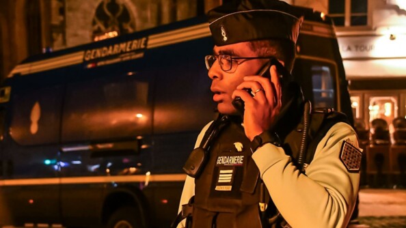 Un officier de gendarmerie au téléphone de nuit devant un véhicule de la gendarmerie.