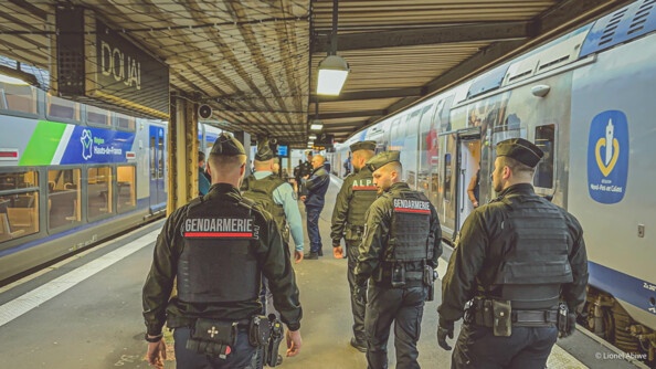 Cinq gendarmes dans une gare entre deux trains.