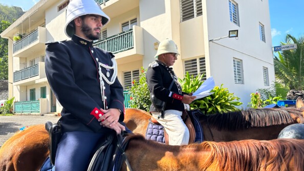 Un gendarme et un acteur en uniforme d'époque montent à cheval.