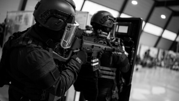 Photo en noir et blanc d'une colonne de gendarmes tenant un bouclier et leur arme.
