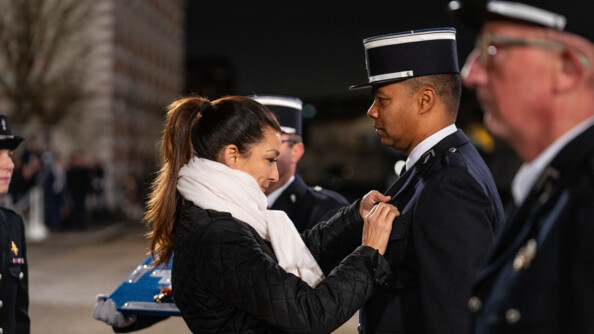 Une femme de profil droit remet une médaille à un gendarme de profil gauche