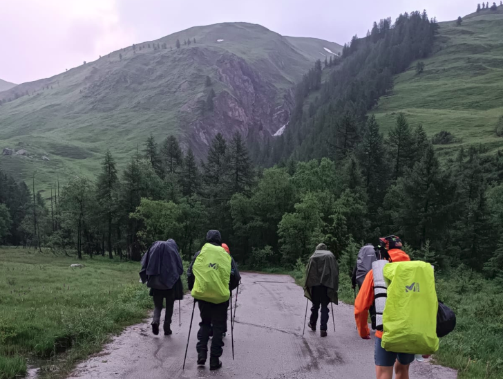 Les randonneurs sous la pluie marchant de dos avec leurs sacs et leurs ponchos.