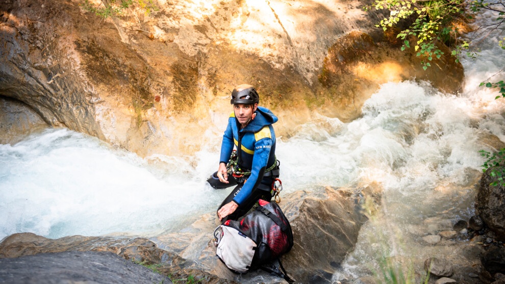 Un gendarme protège son sac de l'eau provenant d'un toboggan naturel.