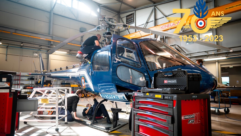 Trois militaires du CNaMAG intervenant sur un AS350 Écureuil à l'occasion d'une opération de maintenance.