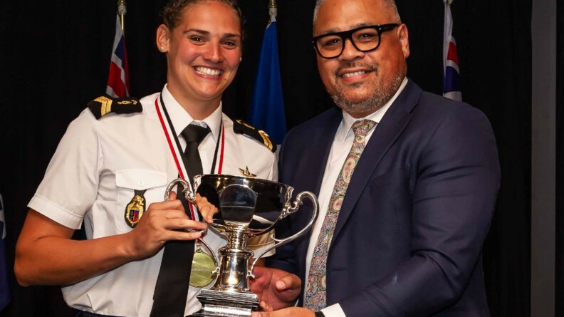 Agrandir l'image Pauline, à gauche reçoit un trophée, en chemisette blanche et cravate, des mains d'un homme en costume à droite.