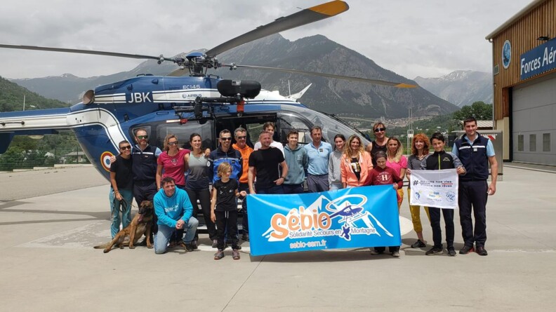 Les participants à cette nouvelle édition de Rêves de Cimes, devant un hélicoptère de la gendarmerie. En fond, on observe les montagnes.