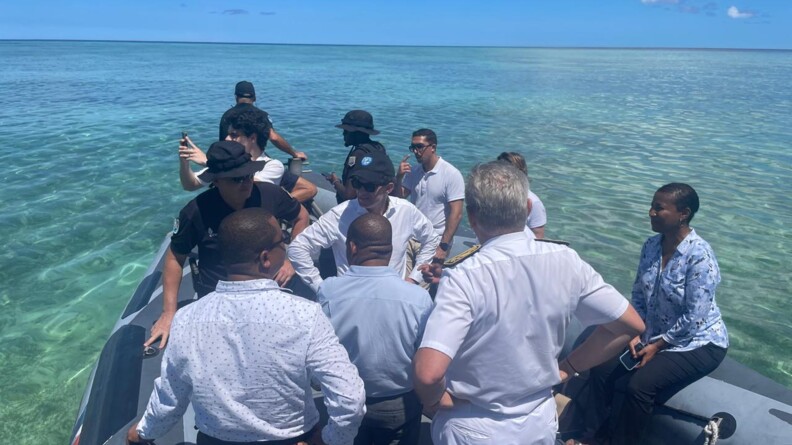 Agrandir l'image Le ministre des outre-mer, vêtu d'une chemise blanche et d'une casquette noire, vu de face. Il est debout, sur une embarcation de la brigade nautique, entouré d'une dizaine de personnes dont trois gendarmes.