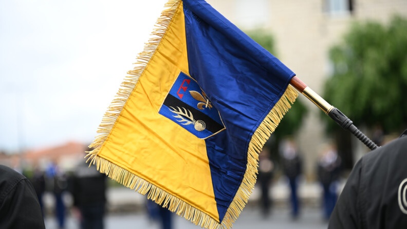 Le fanion jaune bleu d'un escadron de gendarmerie mobile porté au bout d'un FAMAS