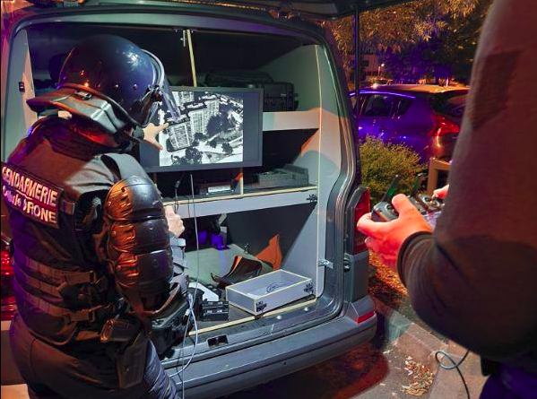 Un opérateur drone oberve sur un écran les images du drone survolant des immeubles.