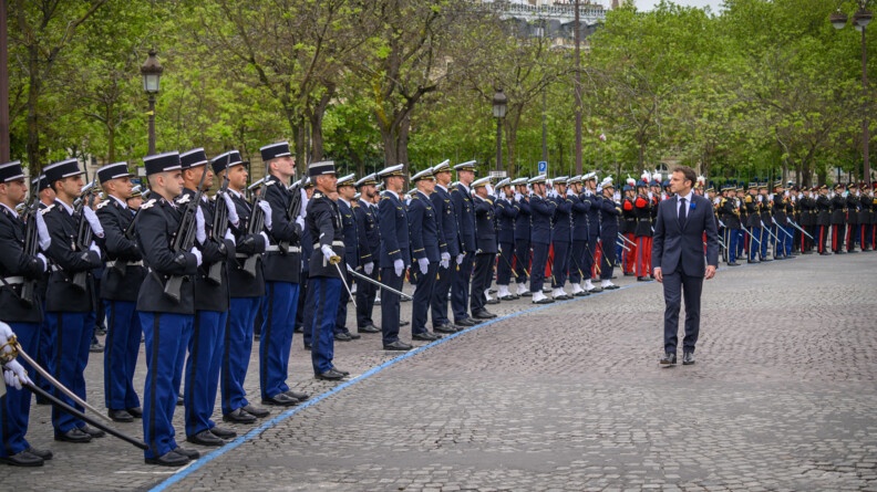 Le président de la République effectue la revue des troupes militaires qui sont alignées devant lui.