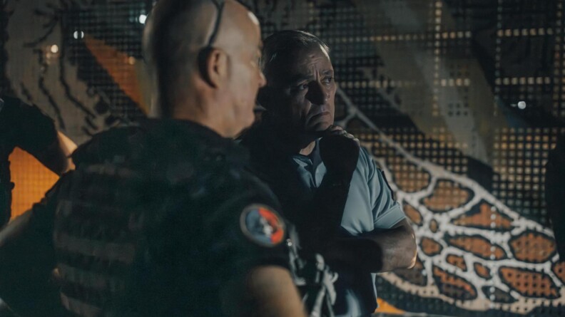 La directeur g&eacute;n&eacute;ral de la gendarmerie en train d'&eacute;changer avec un gendarme de dos. Les deux portent un gilet par balles. Il fait nuit et sombre.