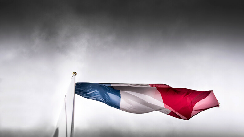 Drapeau en berne dans un ciel gris orageux.