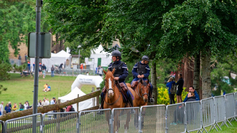 Agrandir l'image Deux gendarmes de la garde républicaine à cheval avec en fond, l'évènement. Ils sont en extérieur et il fait jour.