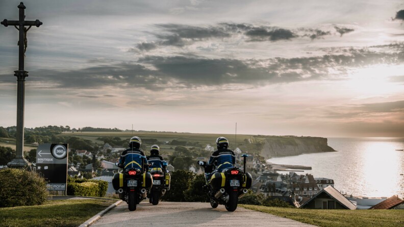 Trois motards de la gendarmerie sur une route avec en fond, les falaises de la côte normande.