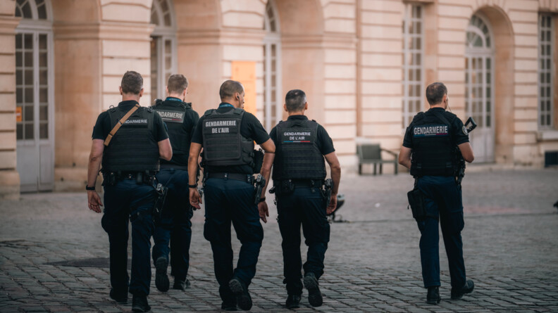 Cinq gendarmes de dos dont deux gendarmes de l'air patrouillent devant le château de CHambord