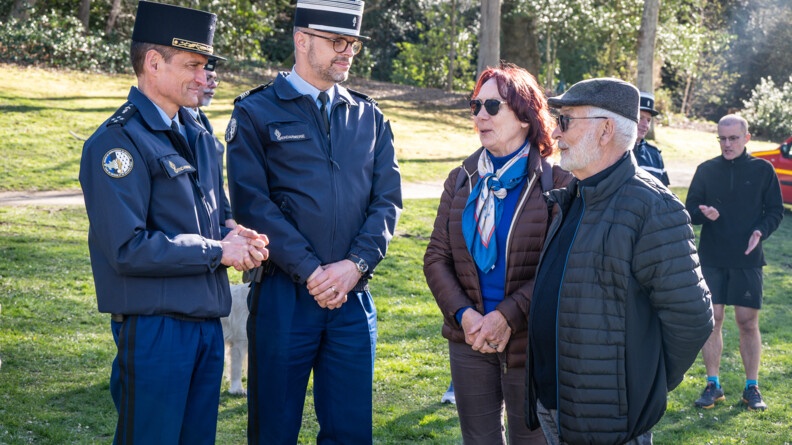 Photo d'un homme et d'une femme relativement âgés, discutant avec deux gendarmes, dans un parc.