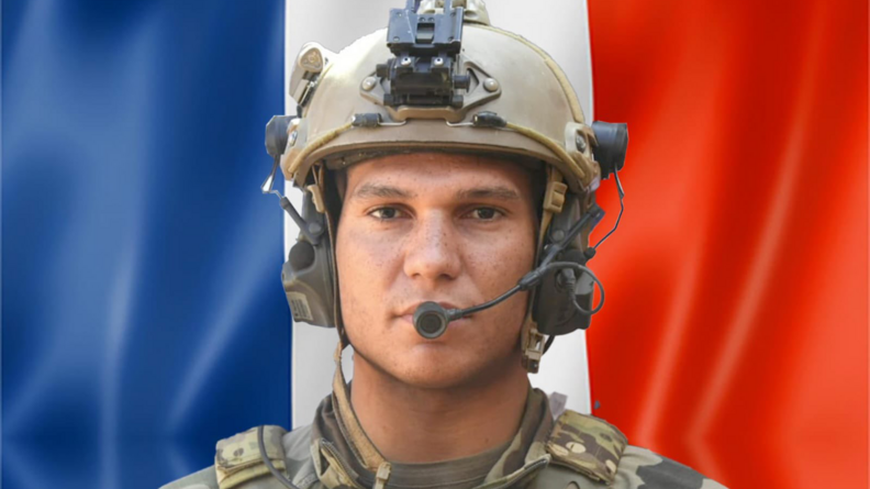 Photo montrant l'ISG1G Bonnemere en treillis et casque lourd avec le drapeau tricolore en arrière plan.