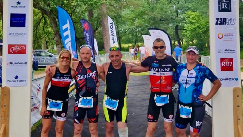 Un groupe de 5 sportifs se tiennent par les épaules sous un porche d'arrivée de course. A droite et à gauche ce sont deux femmes, au milieu tois hommes. Le plus au centre porte une prothèse à la jambe gauche