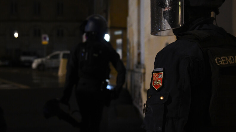 Deux gendarmes casqués de nuit l'un derrière l'autre dans les rues.