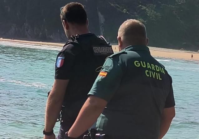 Agrandir l'image Deux agents, l’un de la Gendarmerie française et l’autre de la Guardia Civil espagnole, se tiennent côte à côte face à la mer, sur une plage.