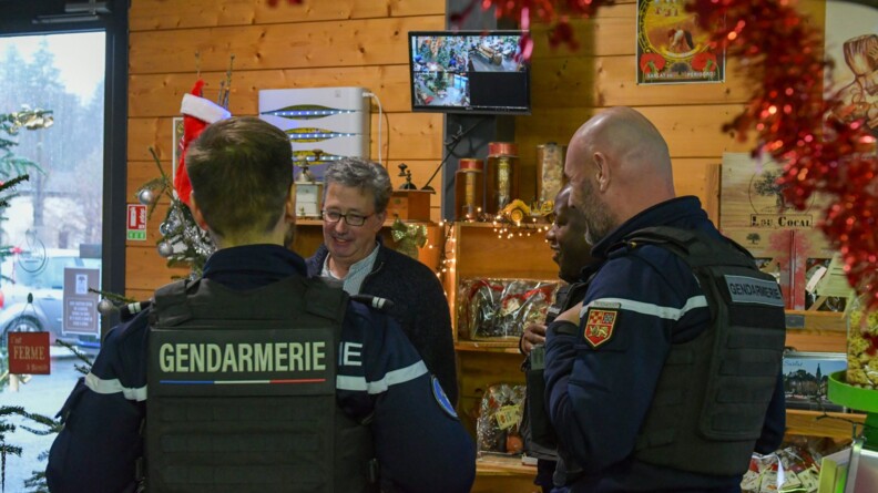 Trois gendarmes dans la boutique d'un commerçant décorée pour Noël